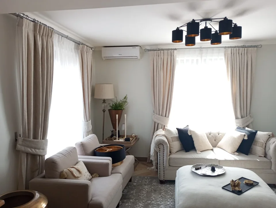 Living con cortinas de tela claras y ventanales en dos muros