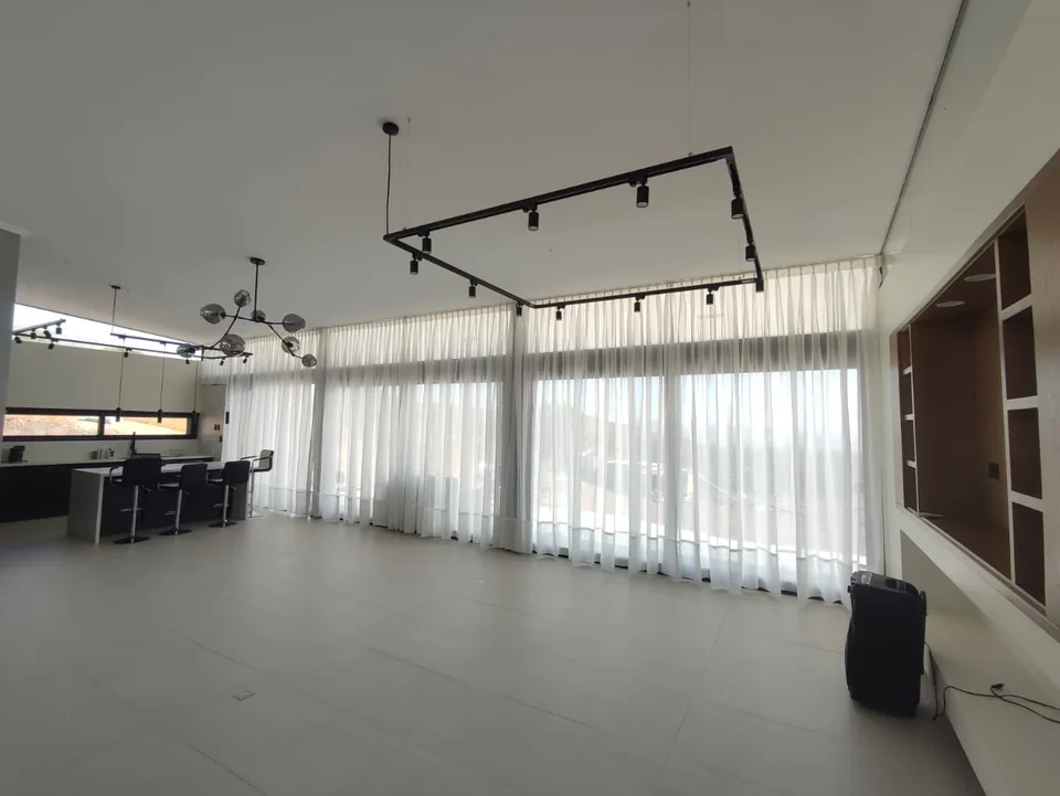 Cortinaje de tela en un salón amplio con ventanales
